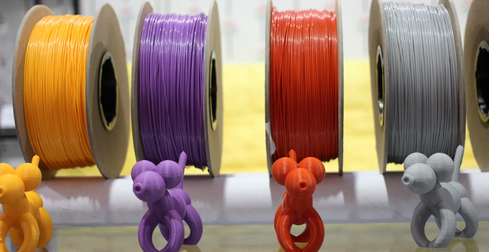 Farklı renklerde PLA, PETG, ABS ve TPU filament makaraları ve bu malzemelerle basılmış örnek parçalar